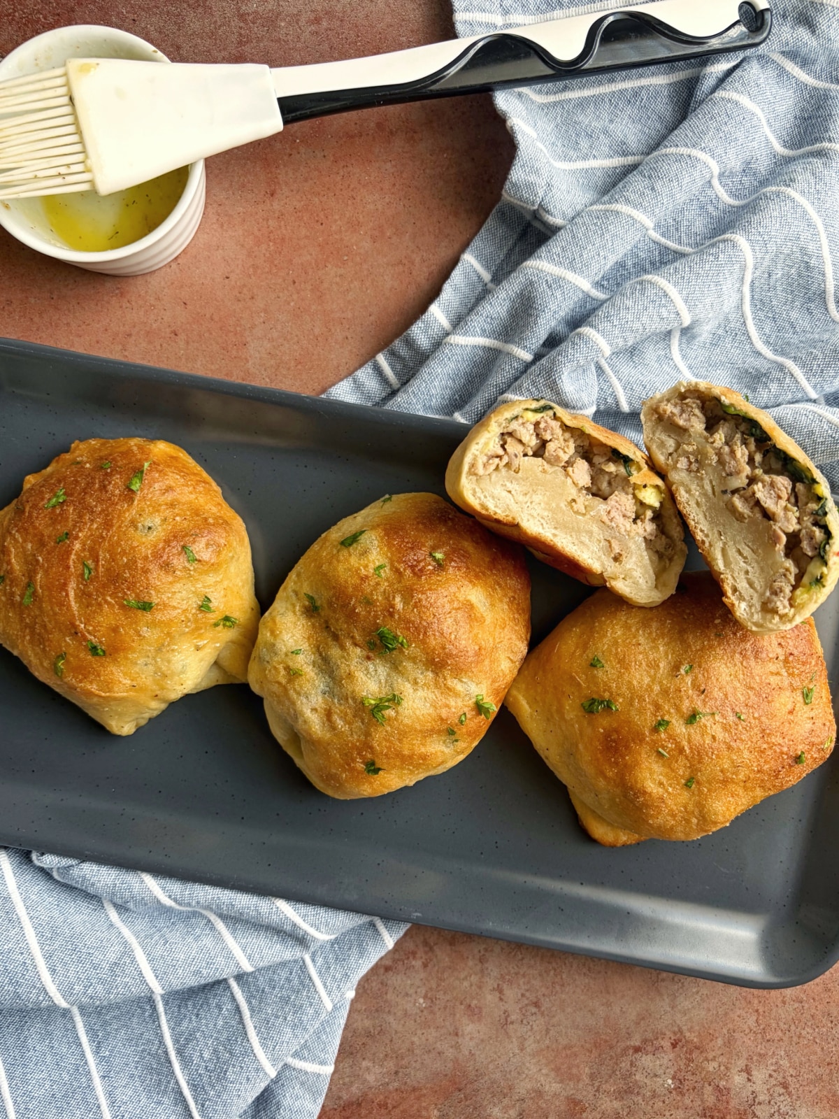 A tray of three breakfast pizza pockets and one that has been sliced in half to display the interior texture.