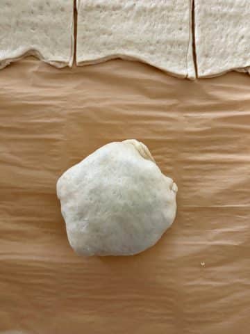 An unbaked breakfast pizza pocket on a parchment-lined tray.