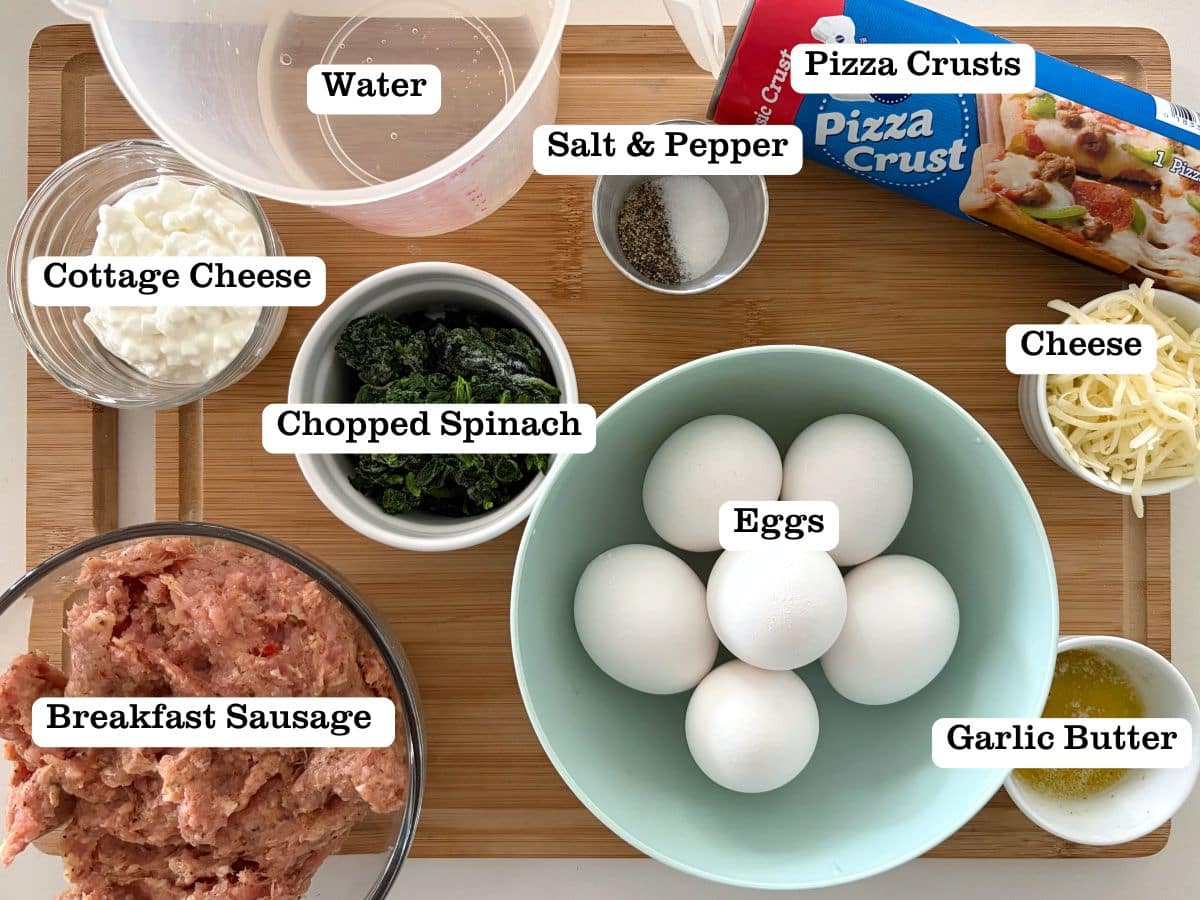 A wooden board containing ingredients to make copycat breakfast hot pockets, including pizza dough, breakfast sausage, and eggs.