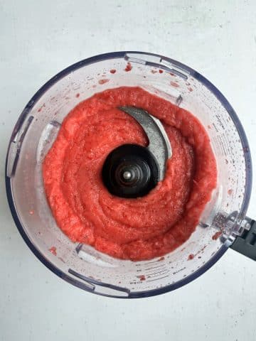 A food processor cup filled with strawberry sorbet.