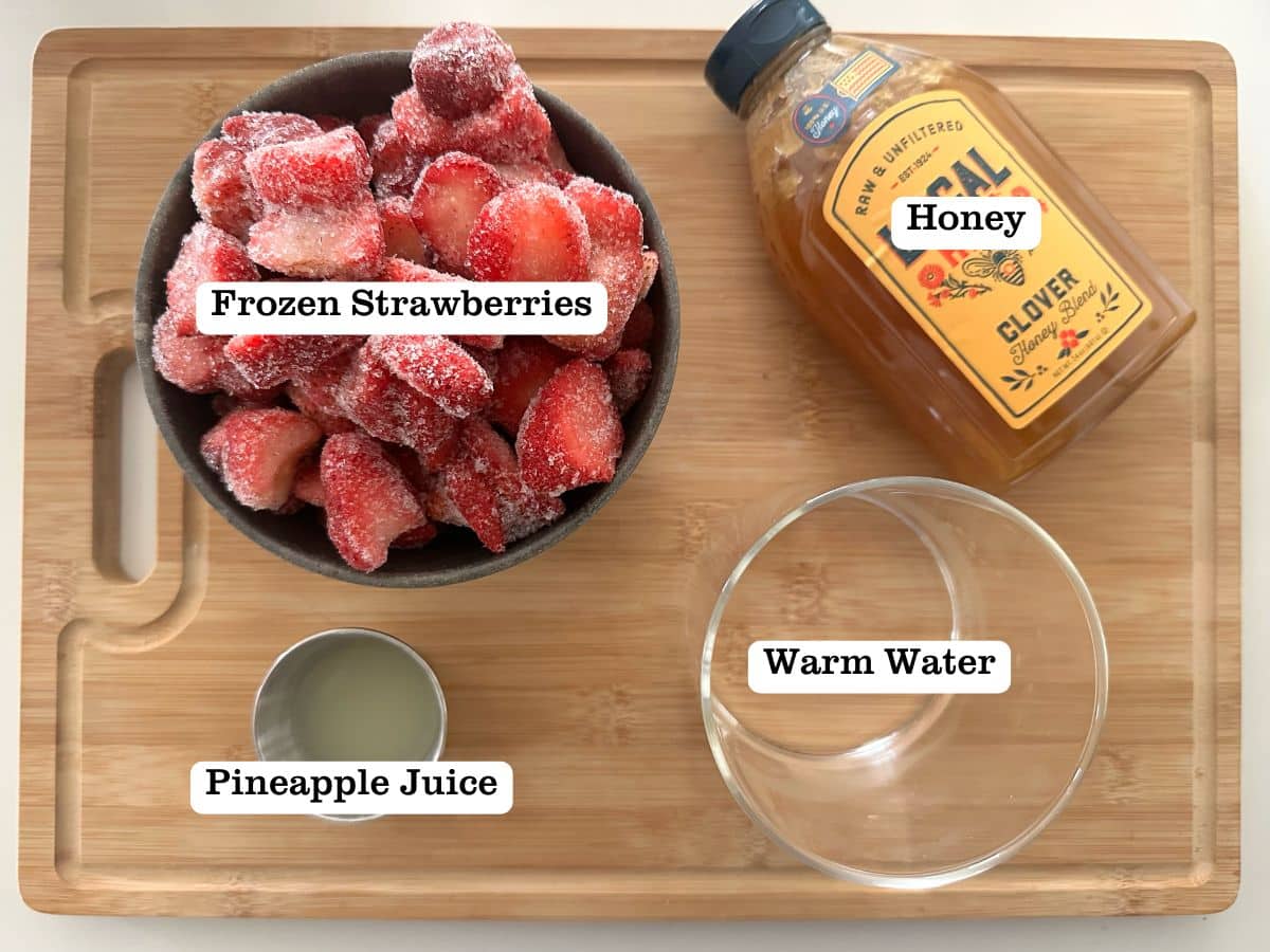 A wooden board containing bowls of ingredients for strawberry sorbet.