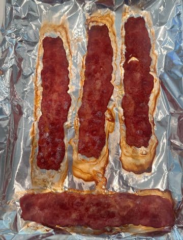 A sheet pan lined with foil, topped with cooked turkey bacon.