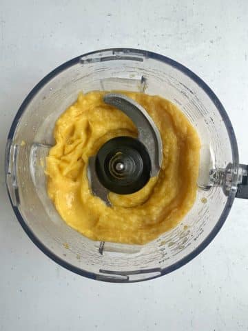 A food processor cup filled with homemade mango sorbet.