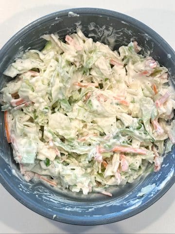 Homemade slaw in a grey mixing bowl ready to be chilled.