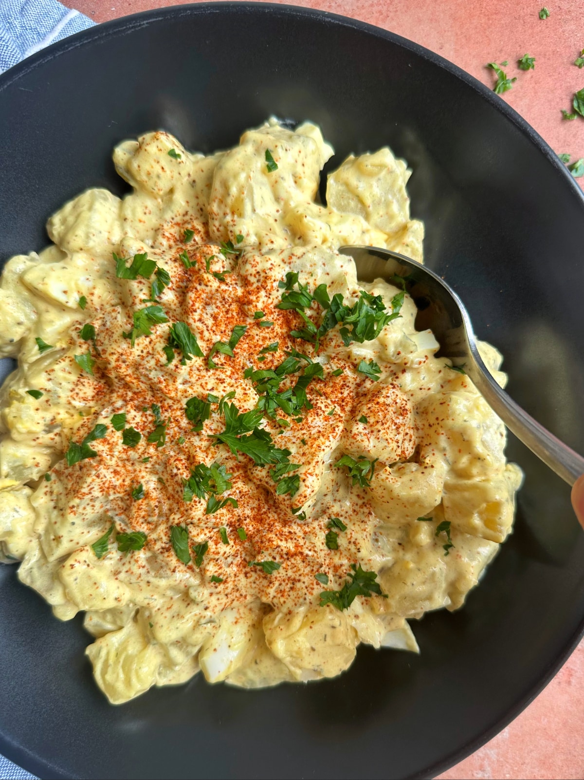 A spoon sticking out of a bowl of potato salad.