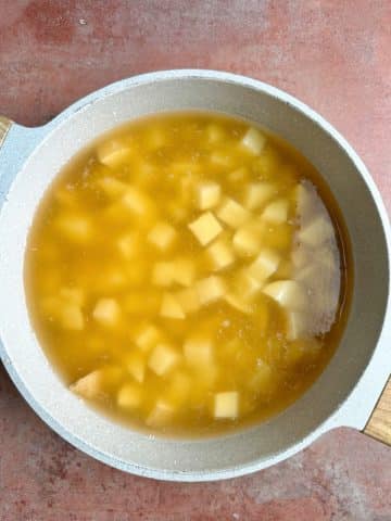 Chopped potatoes in a pot of broth.