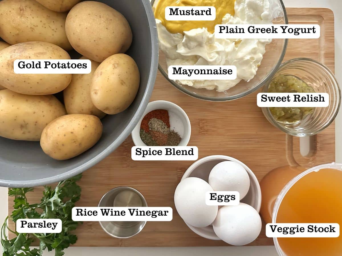 A wooden board containing ingredients for southern-style potato salad in smaller bowls and containers.