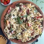 A wooden salad bowl filled with BLT Pasta Salad with serving spoons on the side.