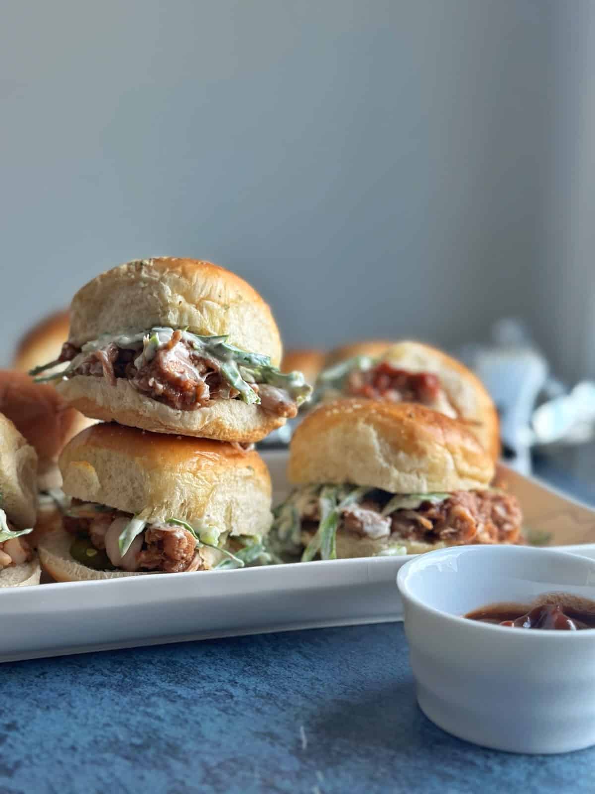 A stack of three BBQ pulled jackfruit sliders with slaw on a white plate.