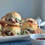 A stack of 3 BBQ pulled jackfruit sliders with coleslaw on a white plate.
