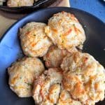 A black bowl filled with homemade cheddar drop biscuits.