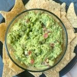A bowl of guacamole surrounded by tortilla chips.