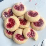 A plate of thumbprint heart cookies with red jam.