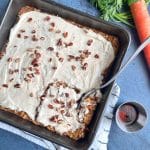 A pan of carrot cake baked oats with cream cheese frosting and pecans on top.