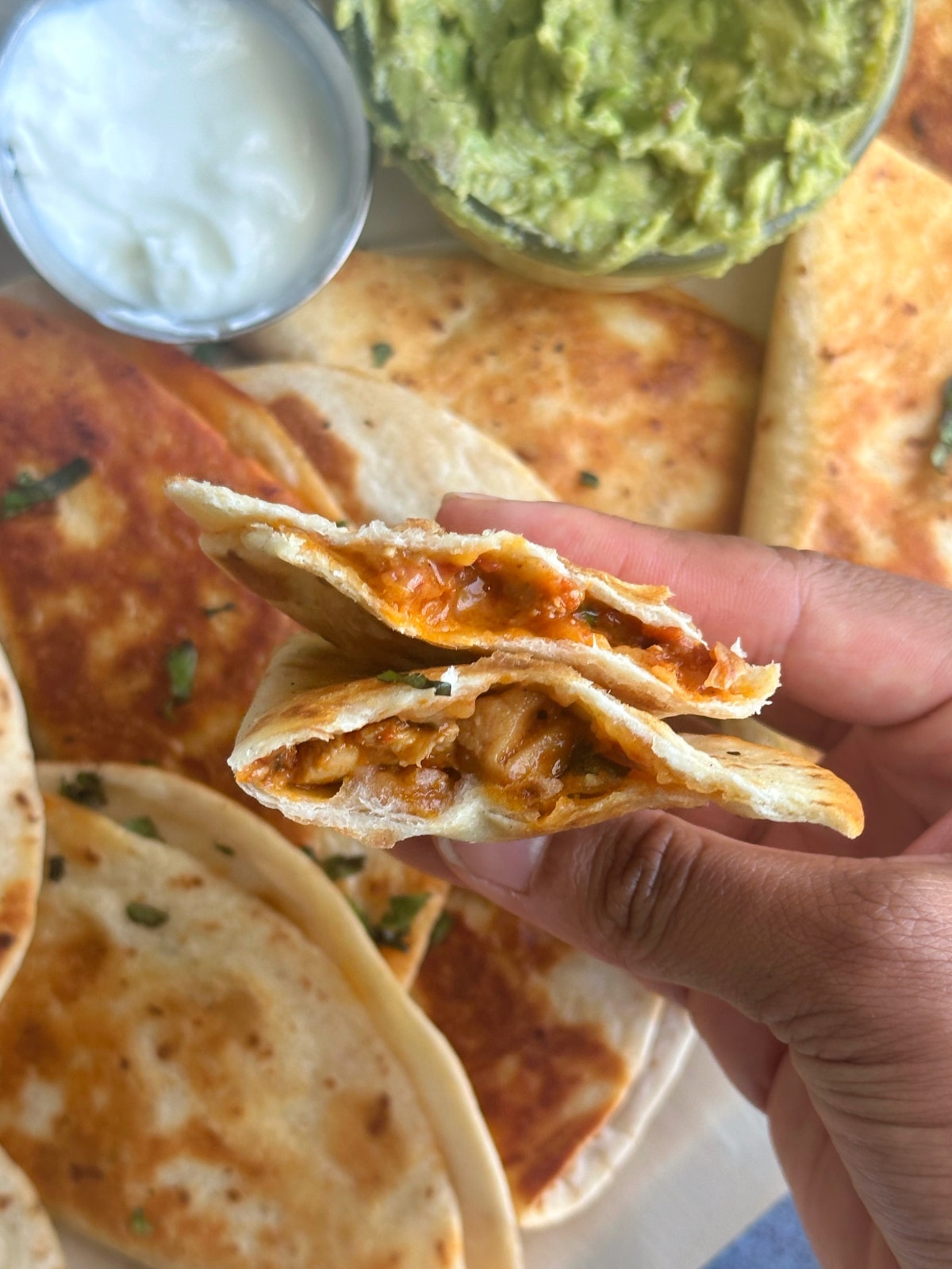 A hand holding two halves of a chipotle chicken taco, so the viewer can see the inside texture.