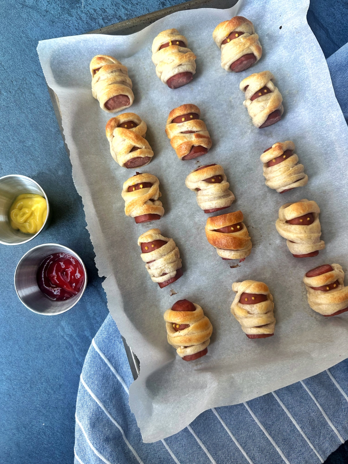 A sheet pan of mini crescent dough-wrapped mummy dogs.