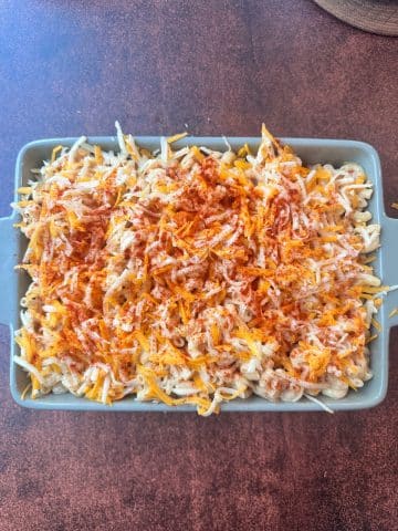 A ceramic dish filled with uncooked macaroni and cheese, right before baking.