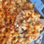 A wooden spoon grabbing a scoop of baked Mac and cheese.