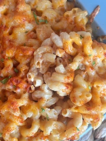 A wooden spoon grabbing a scoop of baked Mac and cheese.