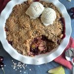 A pie pan filled with cherry apple crisp, and two scoops of ice cream on top.