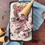 A loaf pan filled with cherry chocolate chip ice cream and sugar cones on the side.