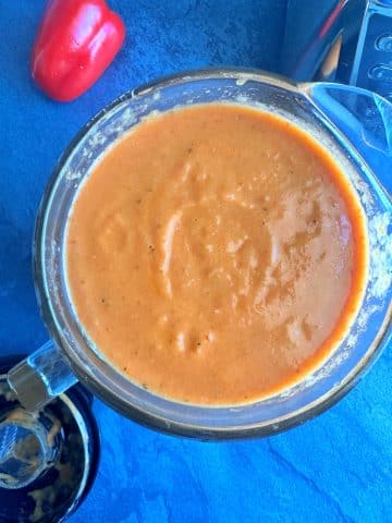 A blender filled with blended vegetables that created a reddish-orange soup.