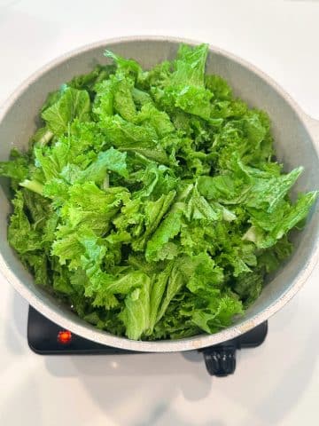 Freshly washed mustard greens in a large dutch oven.
