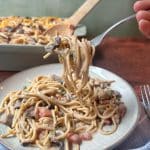 A fork holding up a helping of chicken tetrazzini over a plateful of the rest.
