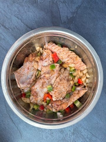 A bowl of turkey wings marinating in seasonings and vegetables.