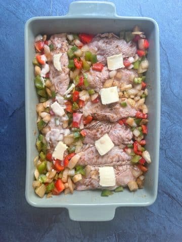 A pan of seasoned turkey wings and onions and bell peppers, about to be baked.