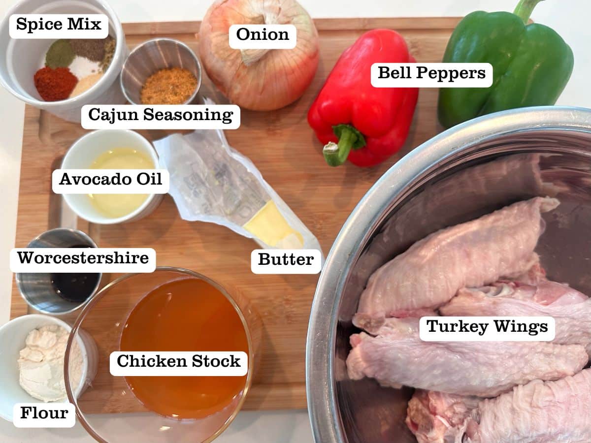 A wooden board containing ingredients for baked turkey wings, including bell peppers, onions, and cajun seasoning.