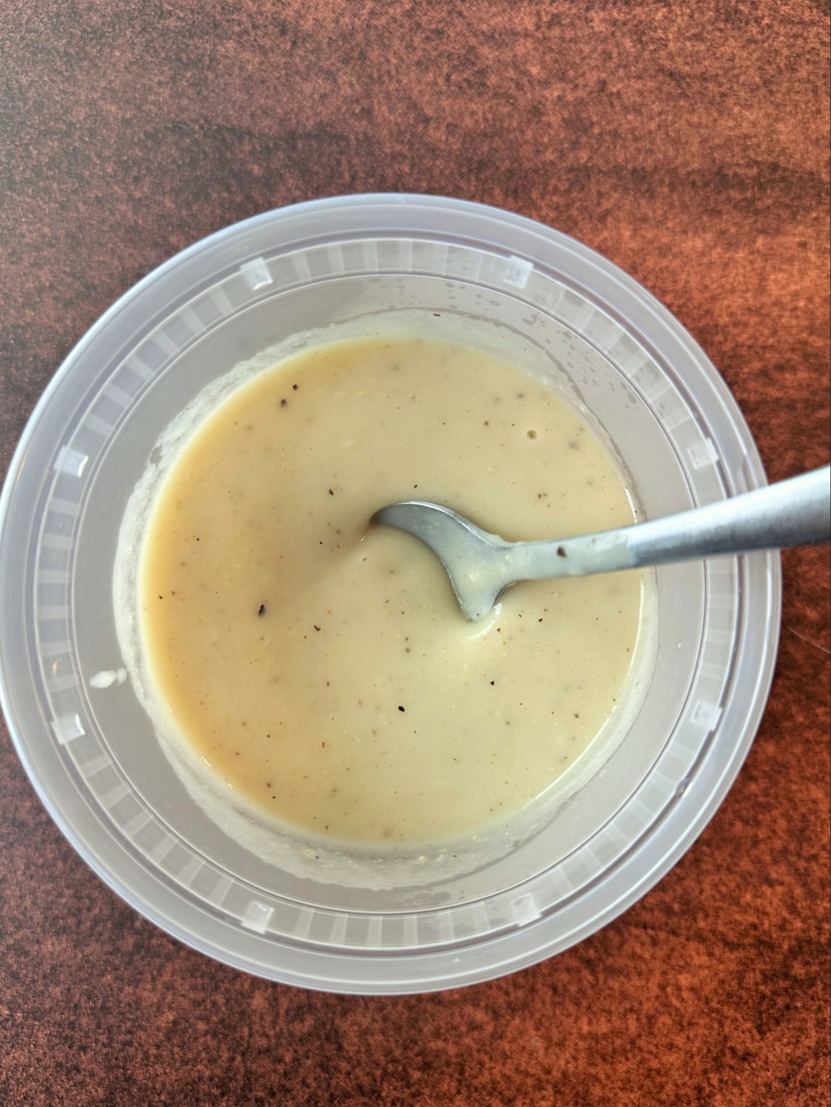 A spoon stuck in the middle of a plastic container filled with homemade cream of chicken soup.