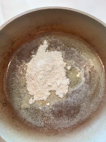 A saucepan with melted butter and all purpose flour poured in the middle.