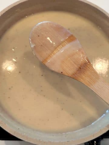 The back of a wooden spoon coated with homemade cream of chicken.