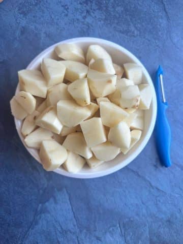 A bowl of peeled and chopped russet potatoes.