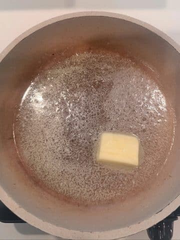 A pat of butter melting in a skillet.