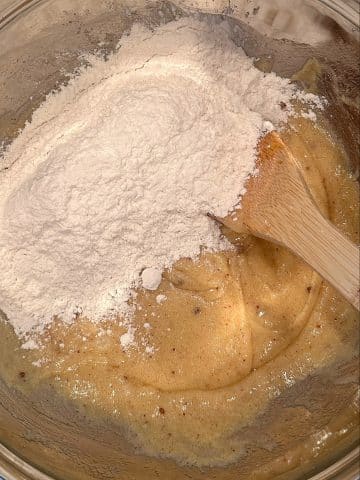 Flour, baking soda, cornstarch, cream of tartar, and salt being added to a mixing bowl of creamed sugar and butter.