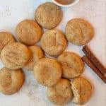 A pile of brown butter snickerdoodle cookies with cinnamon sticks on the side.