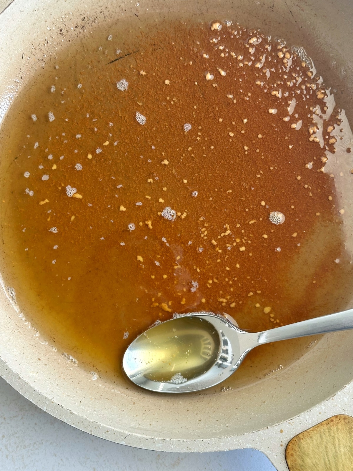 A spoonful of browned butter sitting in a pan filled with the rest.