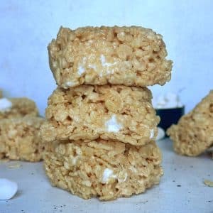 A stack of 3 Brown Butter Rice Krispie treats on a white countertop with more treats in the back.