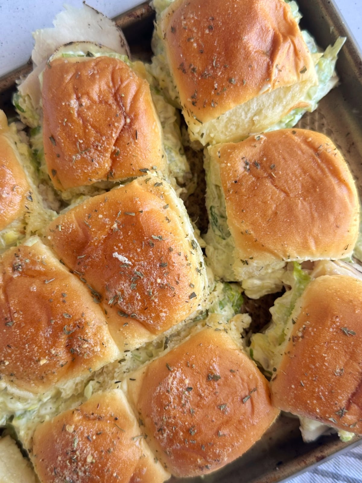 A pan of deli turkey breasts sliders with lettuce slaw.