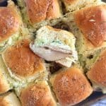 A pan of garlic butter turkey and Swiss sliders with one turned on its side.
