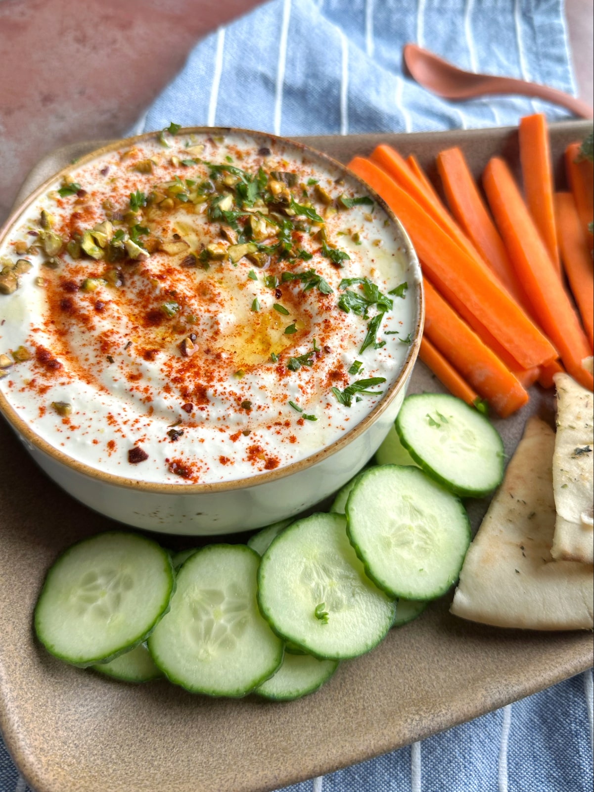 A platter of sliced veggies, pita bread, and a bowl of whipped feta dip.