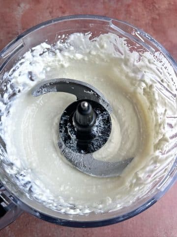 A food processor filled with whipped feta cheese and yogurt.