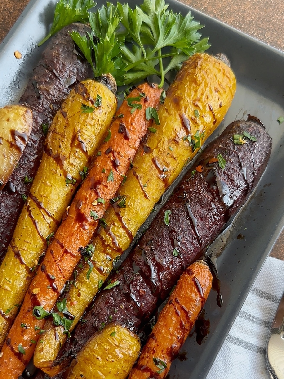 Balsamic Roasted Carrots on a black serving tray with fresh parsley.
