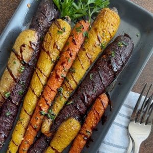 A plate of roasted carrots with balsamic glaze drizzled on top.