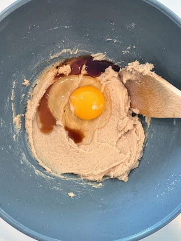 A mixing bowl with creamed butter and sugar, eggs, and vanilla extract.
