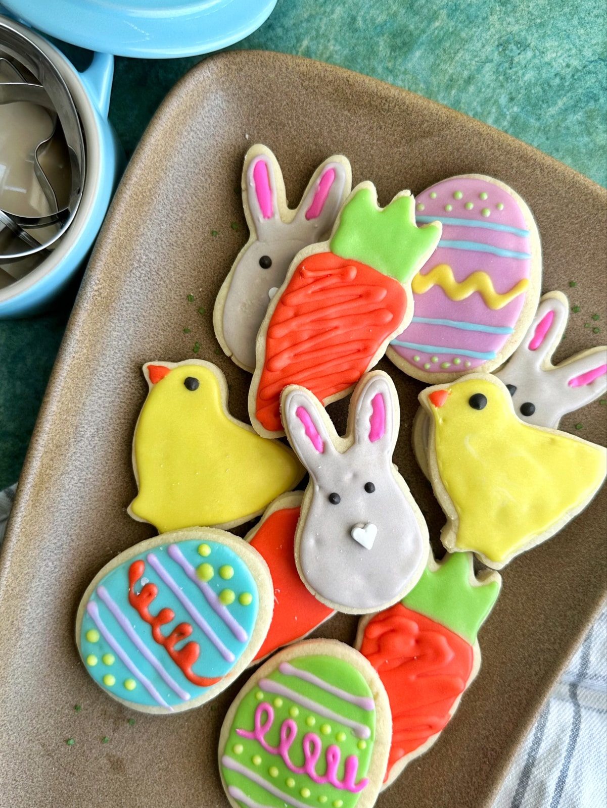 A tray filled with cut out sugar cookies decorated with Easter shapes and colors.