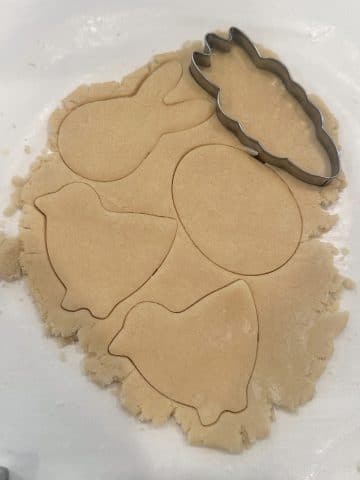 Cookie dough rolled out into a thin layer with Easter shapes cut into the dough.