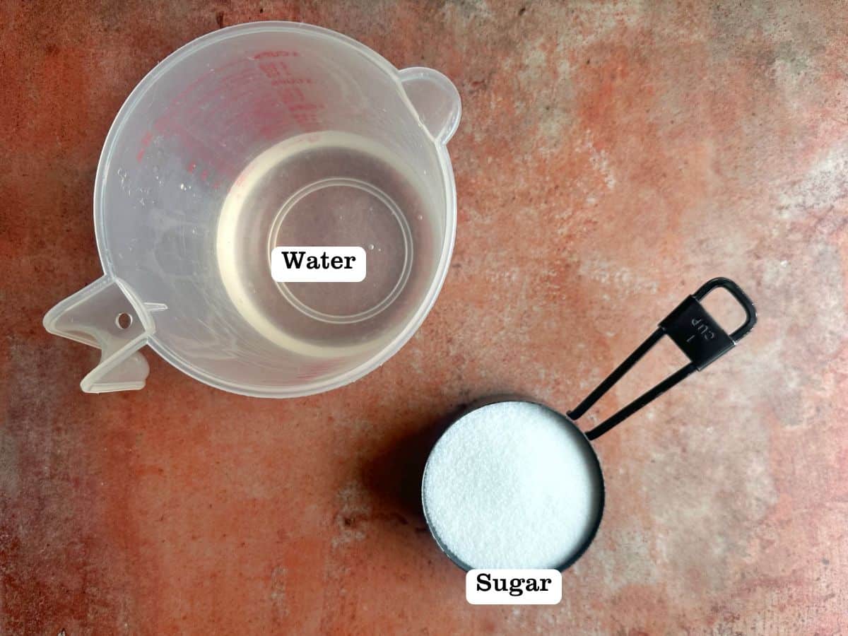 A board containing ingredients for simple syrup - sugar and a container of water.